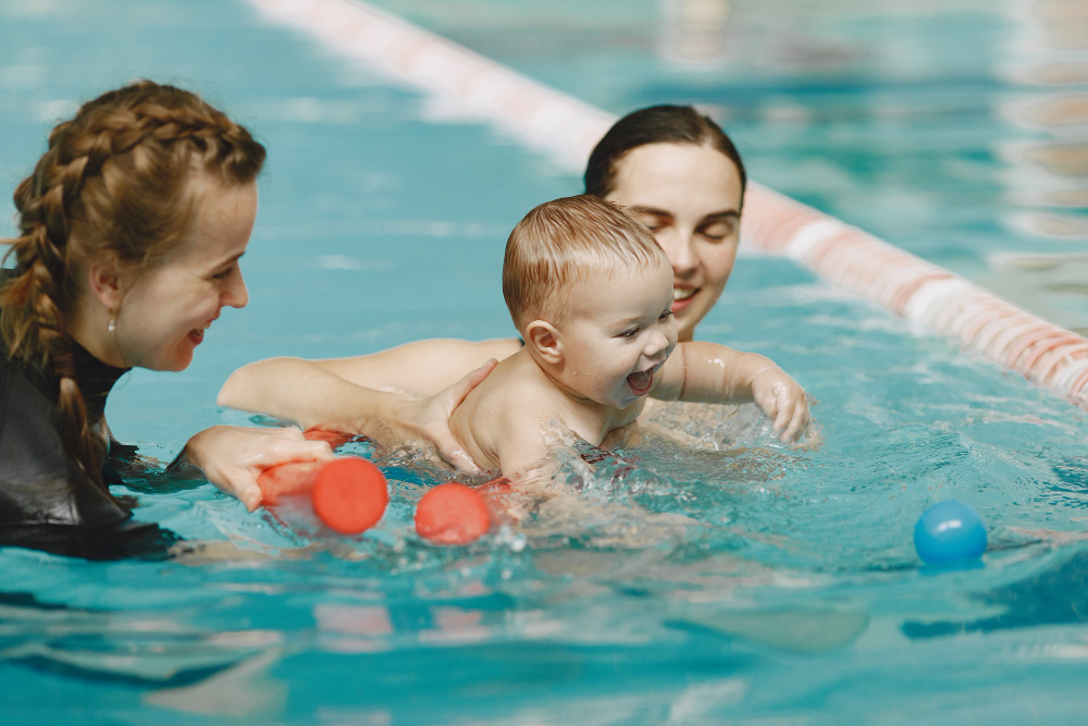 Bebê nadando na piscina com a mãe